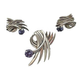 Silver leaf-shaped earrings with purple gemstones on a black background