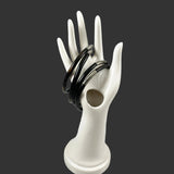 White ceramic hand-shaped holder with black coral bangle bracelets