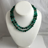 Green beaded necklace on a white mannequin bust against a gray background