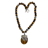 This necklace features natural tiger eye beads and a large, heart-shaped sterling silver pendan
